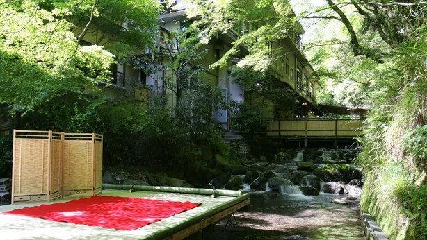 A traditional Japanese ryokan with tatami mat flooring, a wooden platform over a stream, and a bamboo fence. - Kibune Hiroya (Kyoto)