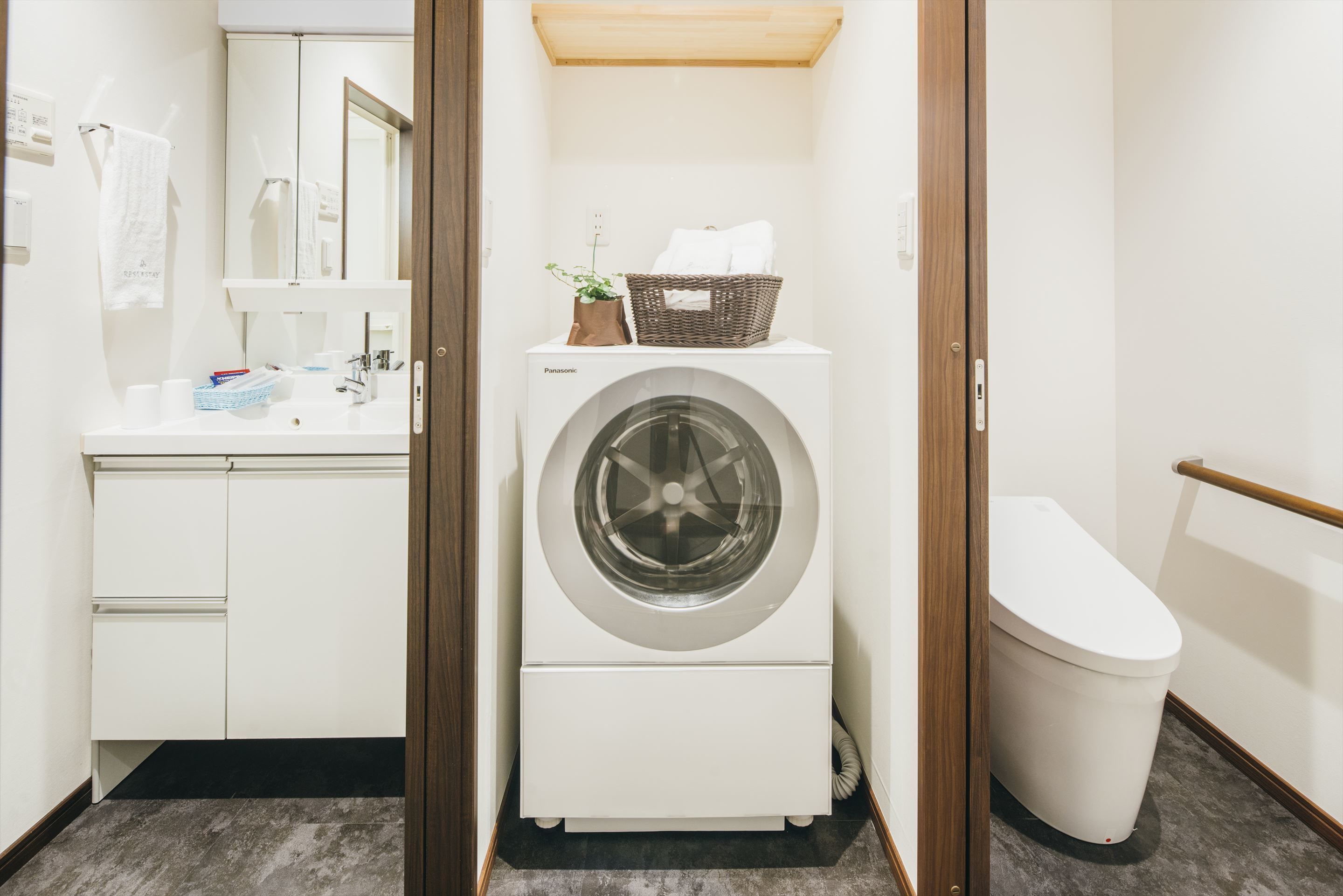 Une petite buanderie comprenant un lave-linge, un petit évier et des toilettes.
