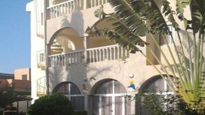 A multi-story hotel with a central courtyard, featuring a tiled walkway and lush greenery. - Residence Diane (Ouagadougou)