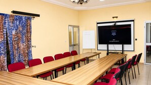 A conference room with a long table, red chairs, a projector screen, and a whiteboard.