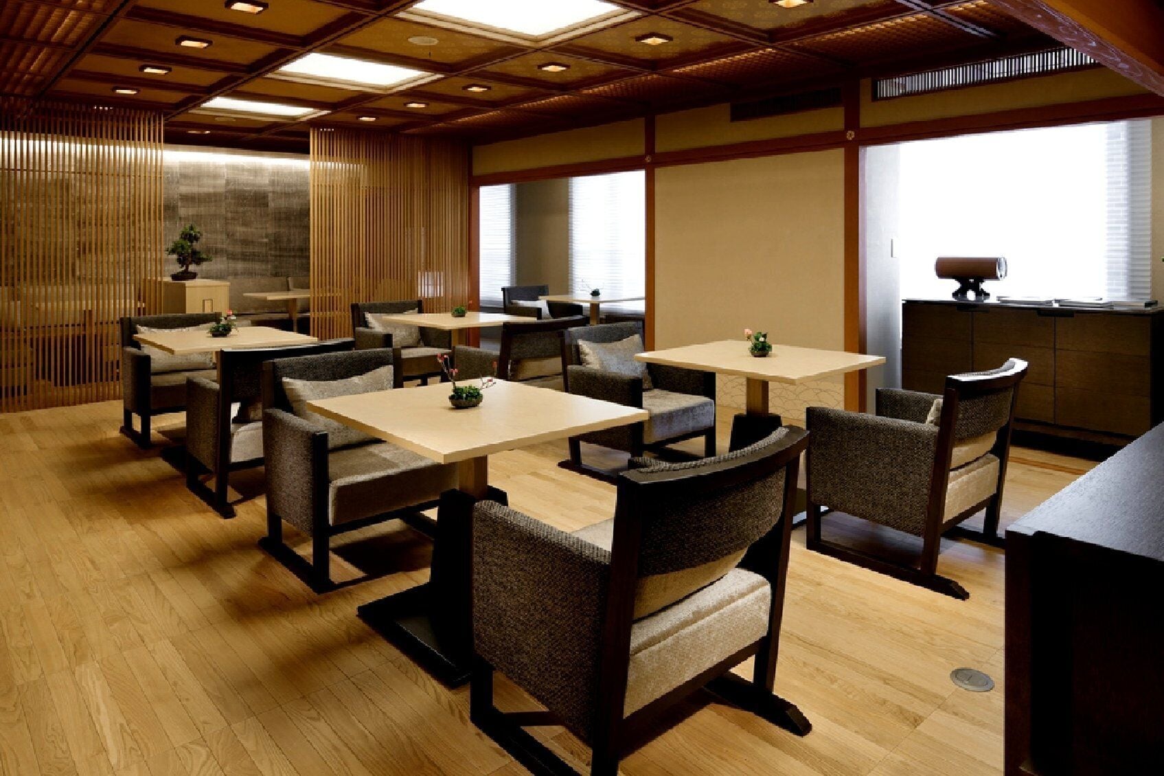 Un restaurant avec un plancher en bois, de nombreuses tables et chaises, et une grande fenêtre équipée de stores.