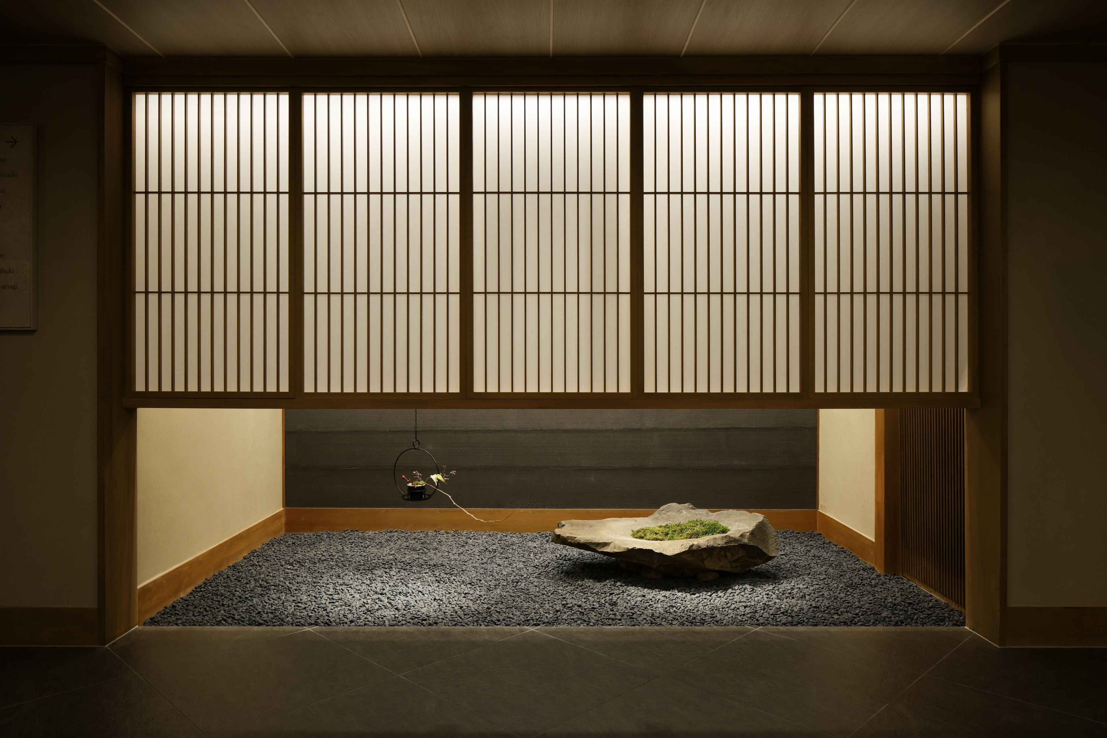 Une pièce de style japonais traditionnel, avec un sol recouvert de tatamis, un paravent en papier de riz (shoji) et un petit jardin de pierres.