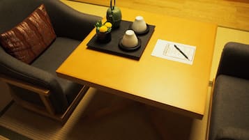 A room with a wooden table, two chairs, a small decorative plant, and a teapot.