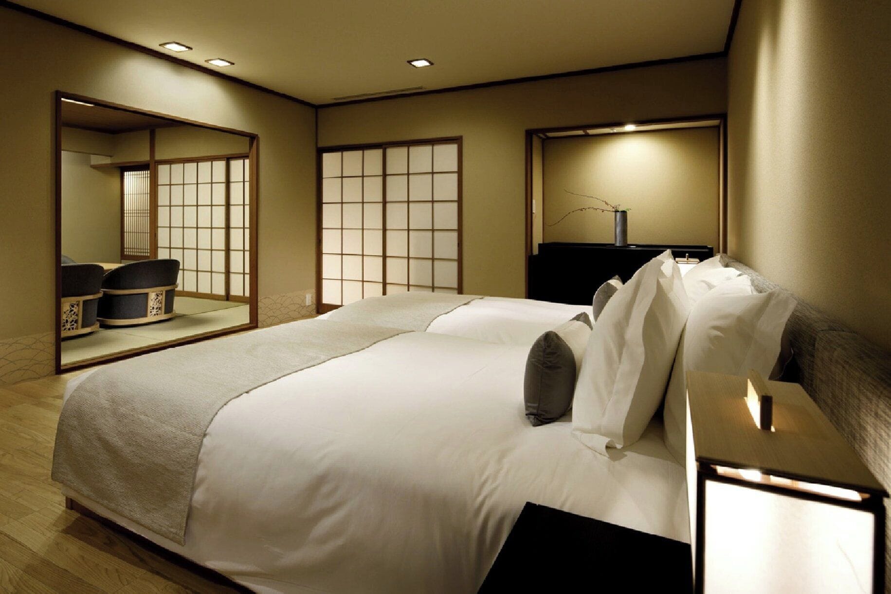 A hotel room with a large bed, a bedside table, a mirror, and a sliding shoji screen.