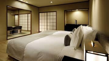 A hotel room with a large bed, a bedside table, a mirror, and a sliding shoji screen.