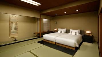 A hotel room with a large bed, a mirror, a nightstand, and a traditional Japanese tatami mat floor.