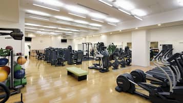 Une salle de sport spacieuse équipée de divers appareils d’exercice, notamment des tapis de course, des appareils de musculation et des poids libres.