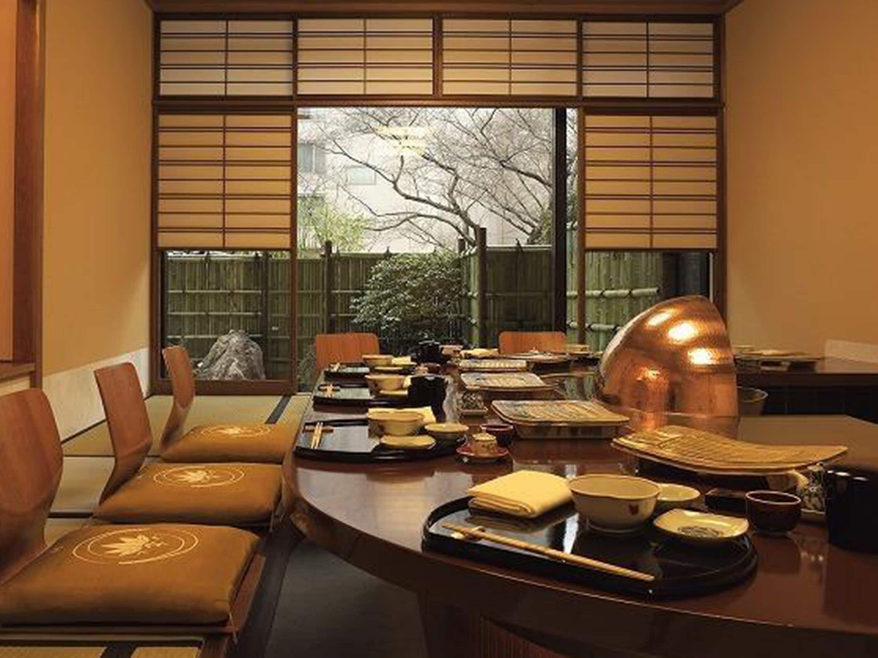 A traditional Japanese-style room with tatami mat flooring, a low table with chopsticks, bowls, and a teapot.