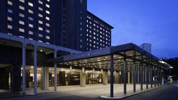 A hotel entrance with a covered walkway, large windows, and a sign for the Grand Prince Hotel Takanawa.
