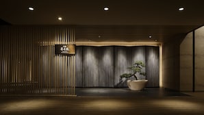A modern interior with a reception desk, vertical wooden slats, a bonsai tree, and a dark wooden floor. - Takanawa Hanakohro, a Member of Small Luxury Hotels of the World (Tokyo)