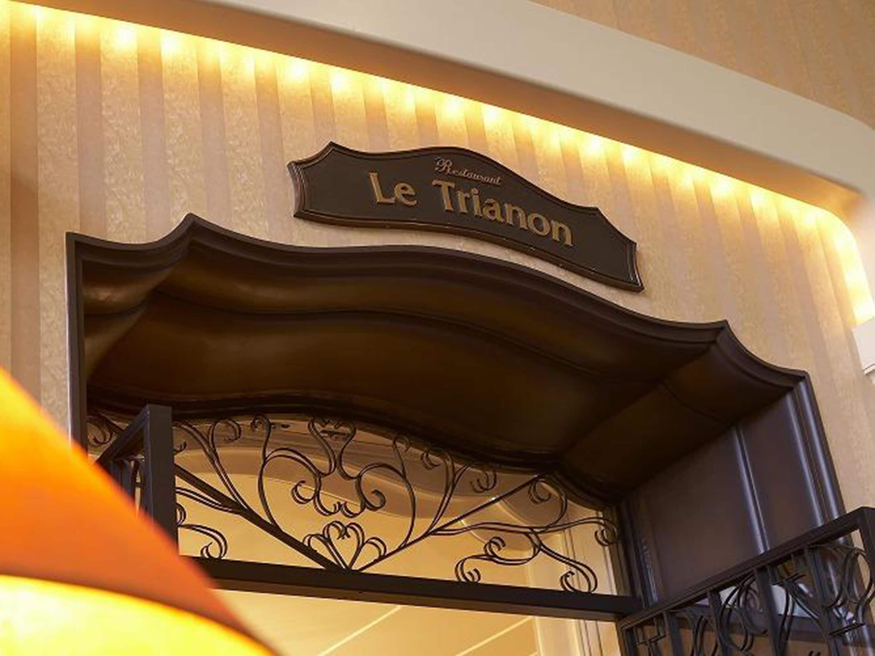 A sign for "Le Triannon" restaurant with a decorative metal gate.