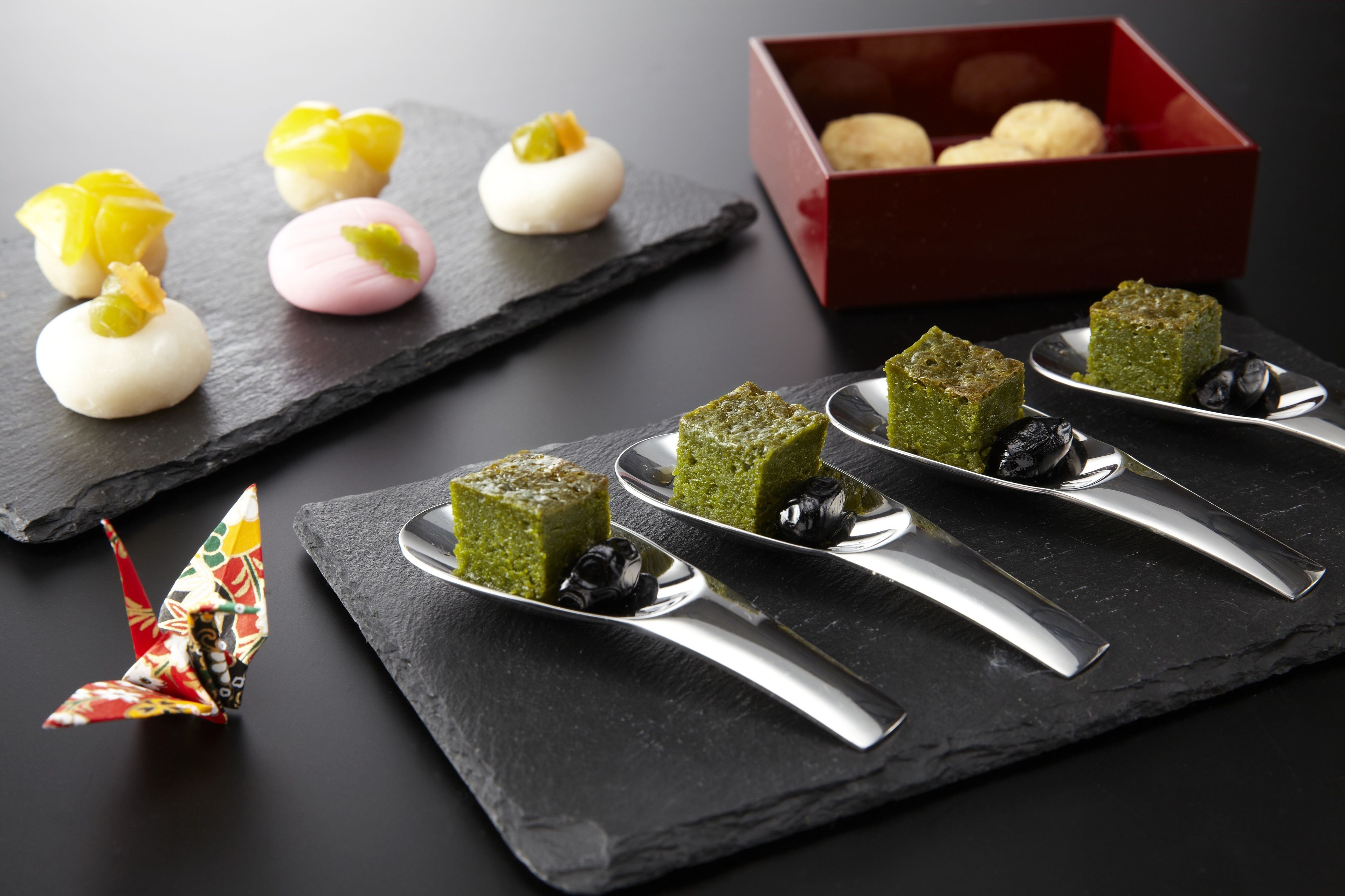 A variety of desserts on slate serving boards, with a red box containing more desserts in the background.