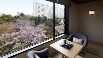 Une pièce avec vue sur les cerisiers en fleurs, une table avec une théière et deux chaises.
