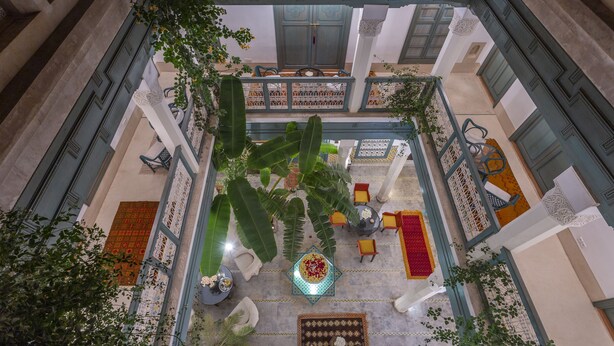 A courtyard with a central fountain, surrounded by seating areas and potted plants. - Riad Azahar (Marrakech)