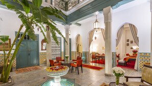 A spacious lobby with a central fountain, seating areas, and a view into a bedroom area. - Riad Azahar (Marrakech)