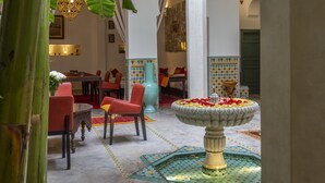 A lobby with a central fountain, seating area, and decorative lighting. - Riad Azahar (Marrakech)