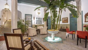 A spacious lobby with a large plant, multiple seating areas, and a decorative fountain. - Riad Azahar (Marrakech)