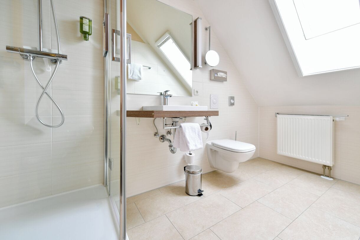 Une salle de bain moderne avec une douche à parois de verre, un meuble-lavabo en bois, des toilettes et un radiateur blanc.