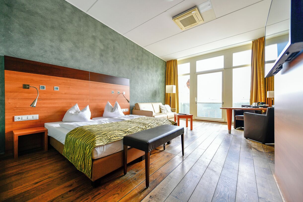 Een hotelkamer met een groot bed, een bureau, een stoel en uitzicht op de stad.