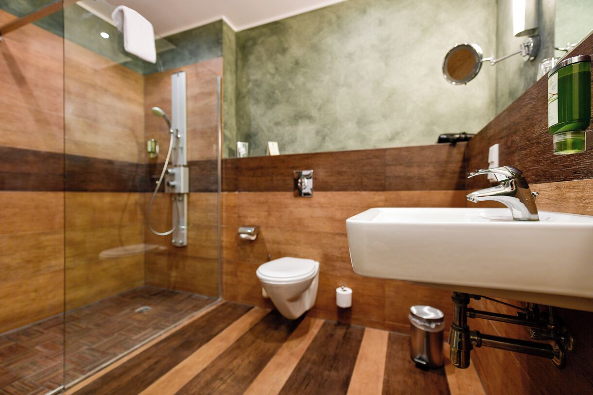 A modern bathroom with a glass shower enclosure, a white sink, and a toilet.