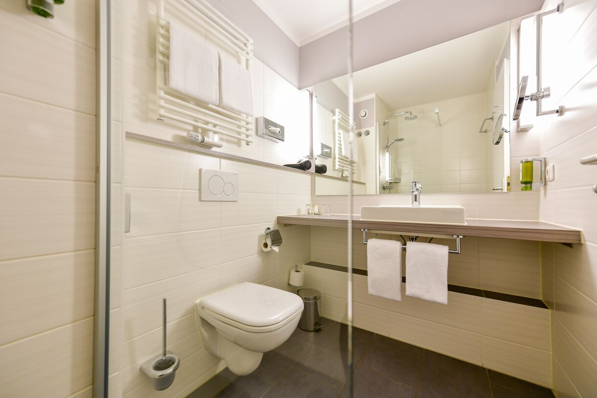 Un baño moderno con inodoro, lavamanos y espejo.