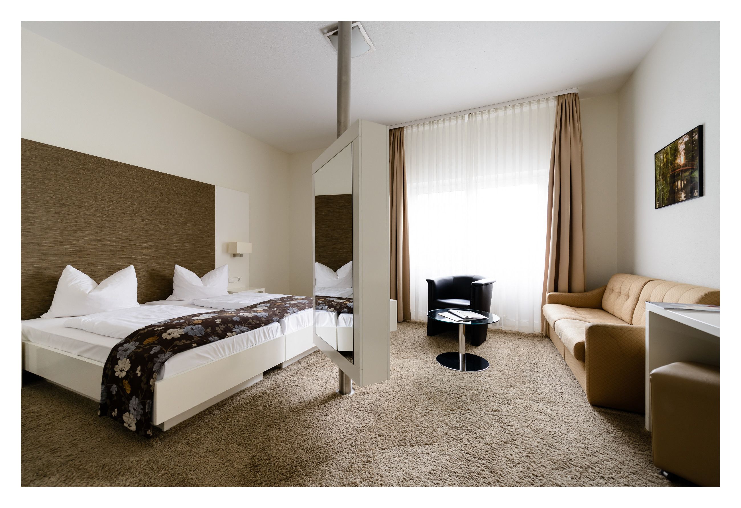A hotel room with a bed, a sofa, a desk, and a chair.