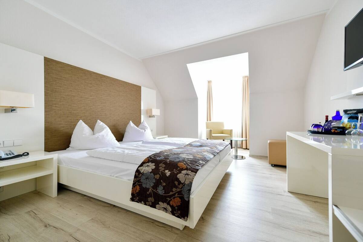 A modern hotel room with a large bed, a desk, and a TV.