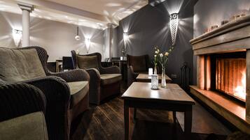 A cozy lounge area with wicker furniture, a fireplace, and wall-mounted lighting fixtures.