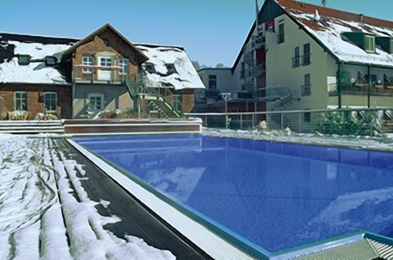 Una piscina con nieve en el borde circundante.