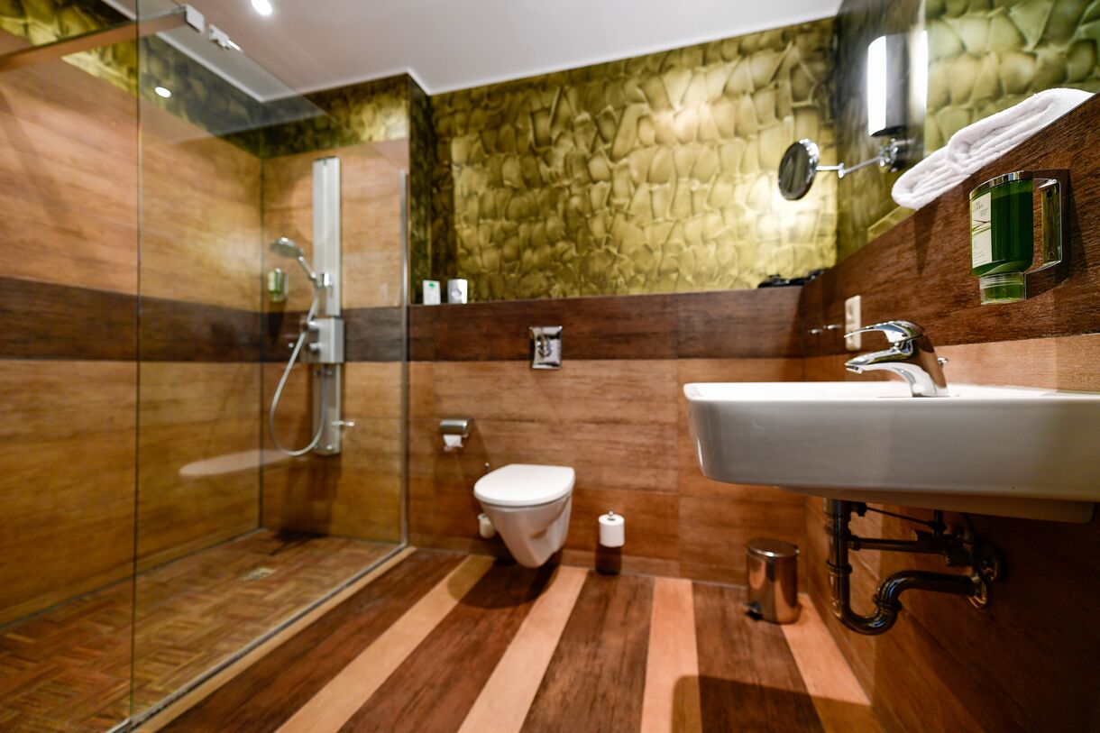 Un baño moderno con cabina de ducha de vidrio, inodoro blanco y lavamanos con espejo.