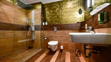 Un baño moderno con cabina de ducha de vidrio, inodoro blanco y lavamanos con espejo.