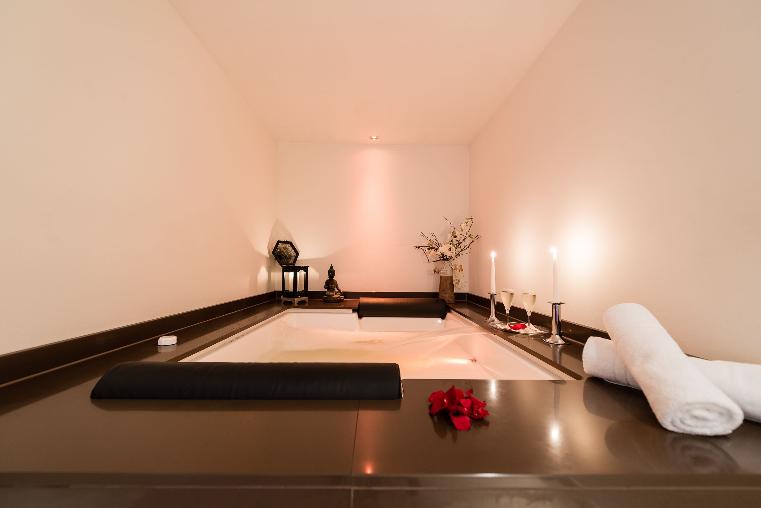 A spa room with a massage table, candles, and towels.