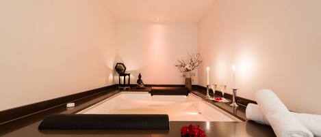 A spa room with a massage table, candles, and towels.