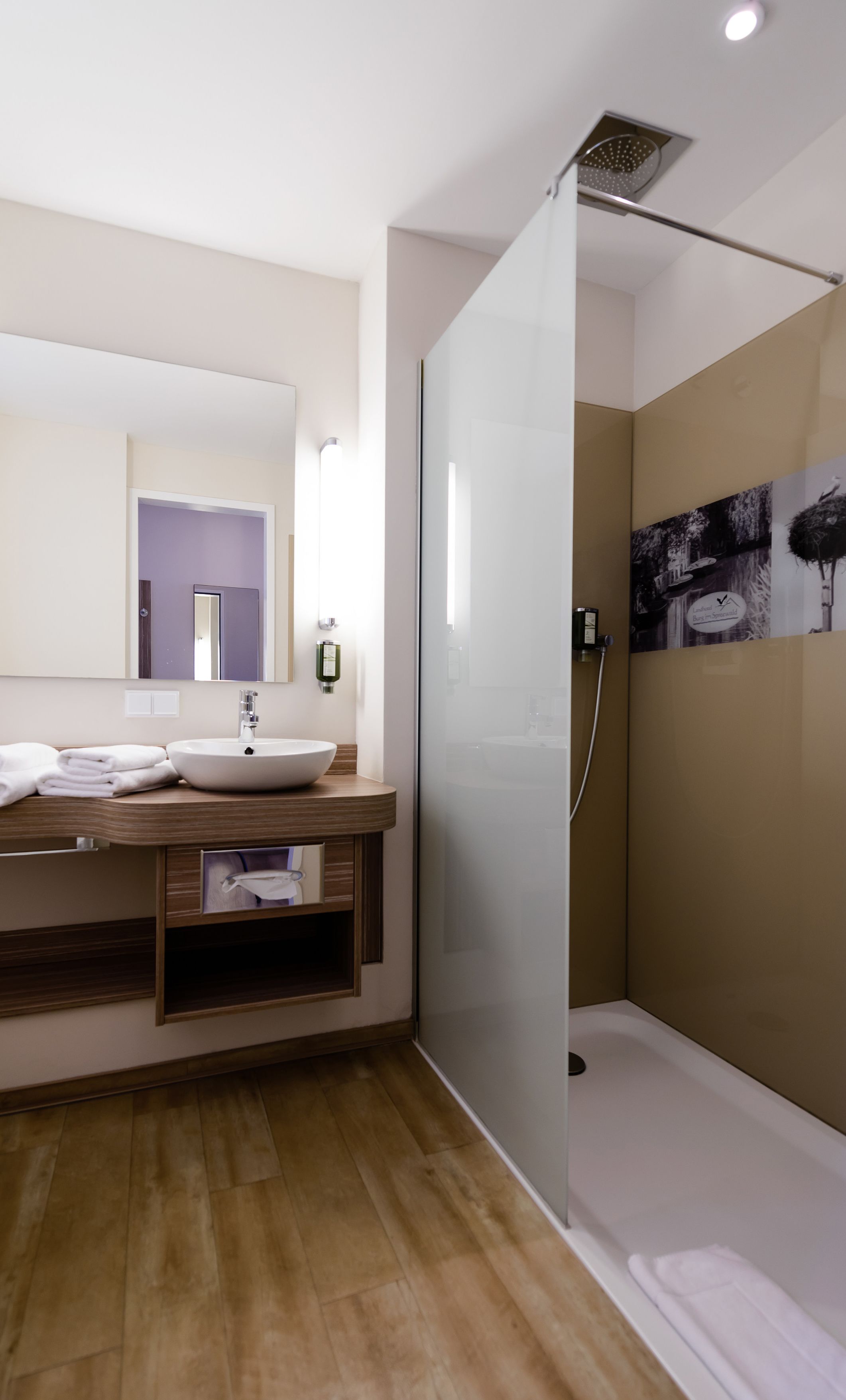 Un baño moderno con un espejo grande, un lavabo y una ducha con mampara de vidrio.