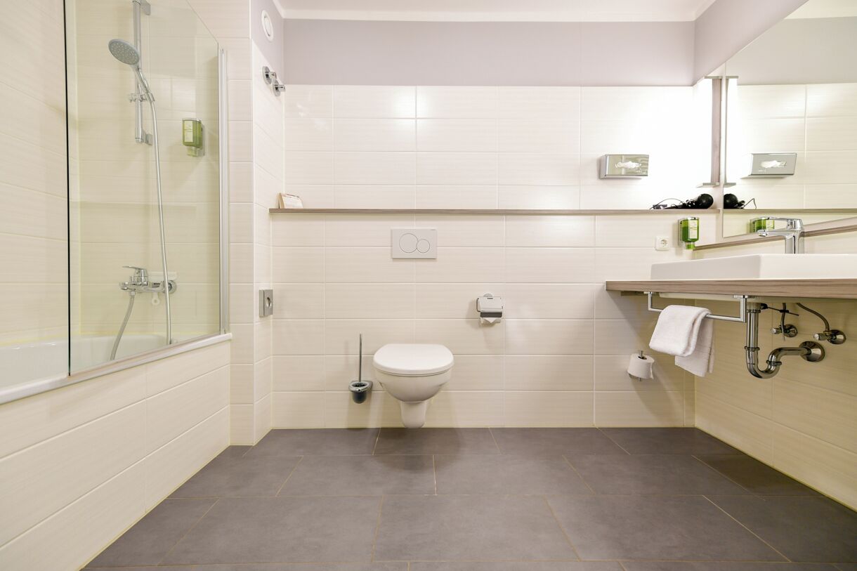Ein modernes Badezimmer mit Duschkabine aus Glas, Toilette und Waschbecken mit Handtuchhalter.