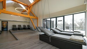 Un spa moderno con vigas de madera, ventanas amplias y varios camastros.