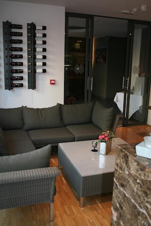 A modern living room with a sectional sofa, a coffee table, and a wine rack. - Hotel Carpinus (Herent)