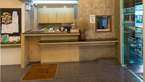 A lobby with a reception desk, multiple clocks on the wall, and a glass door leading to a seating area. - P168 Hostel Samui (Koh Samui)