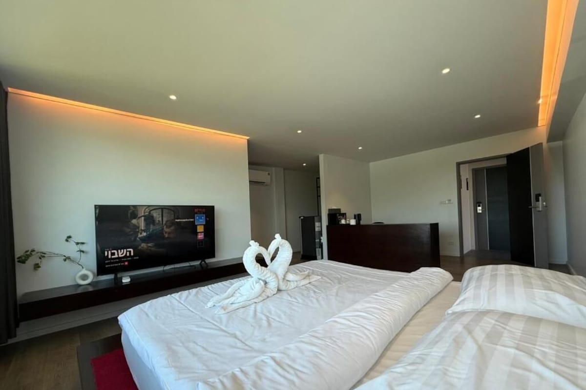 Una habitación de hotel con una cama, un televisor y una alfombra roja.