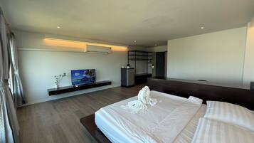 A modern hotel room with a large bed, a flat-screen TV, a small desk, and a built-in wardrobe.