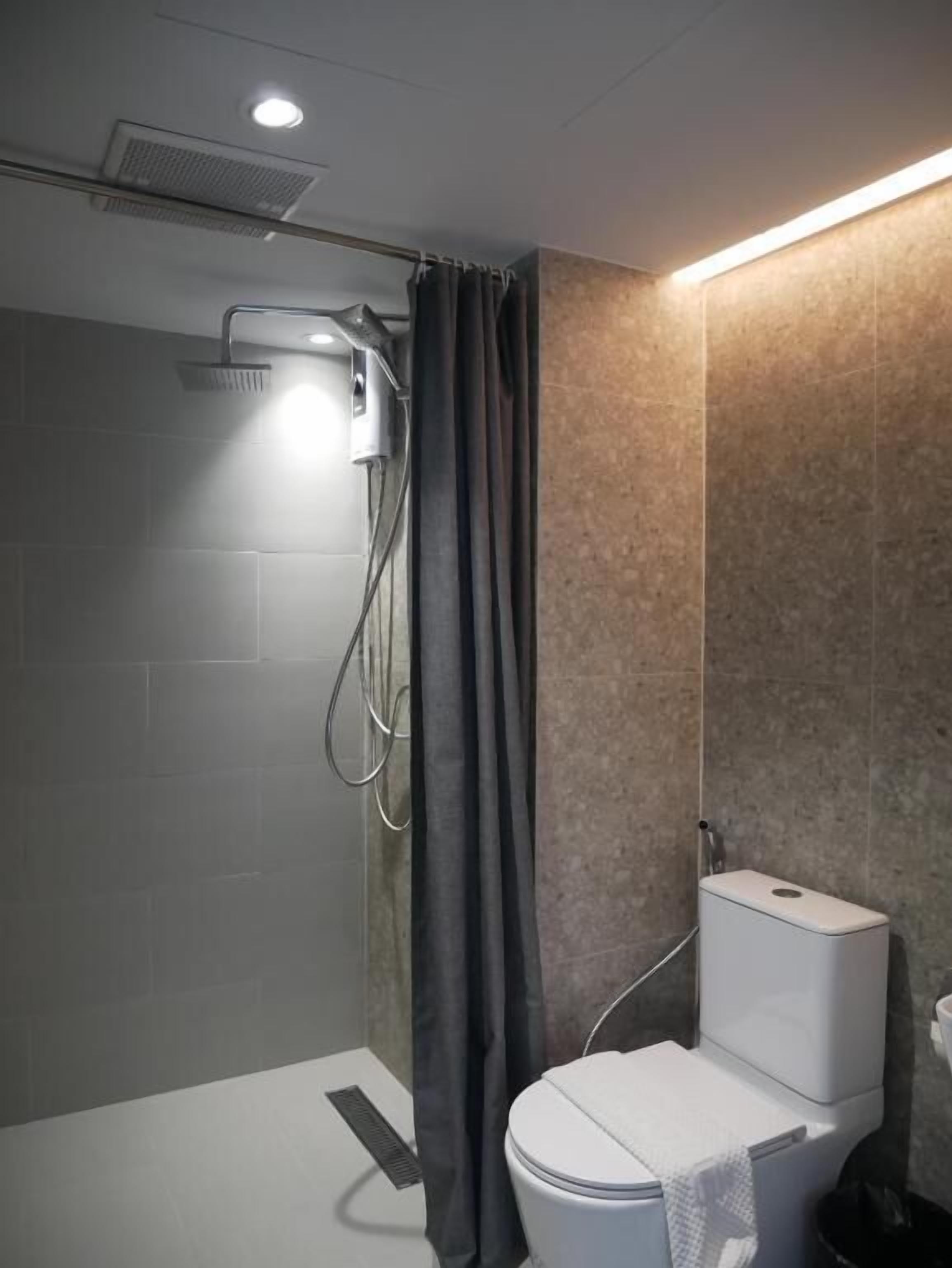 A modern bathroom with a shower, toilet, and a towel rack.