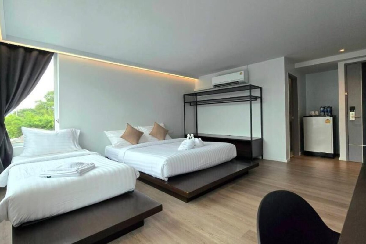 Una habitación de hotel moderna con dos camas, una litera, un escritorio y vistas al exterior.