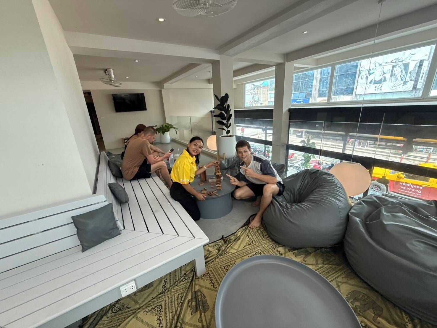 A modern lounge area with seating, a TV, and large windows with city views.