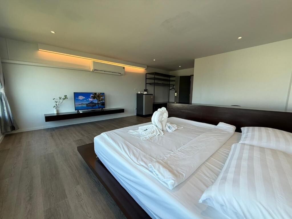 A modern hotel room with a large bed, a flat-screen TV, and a small seating area.