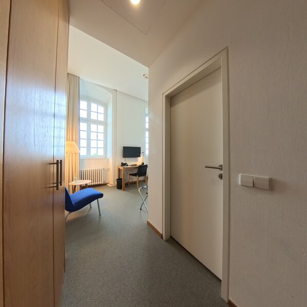 A hotel room with a bed, a desk, a chair, a TV, and a window. - Katholisch-Soziales Institut (Siegburg)