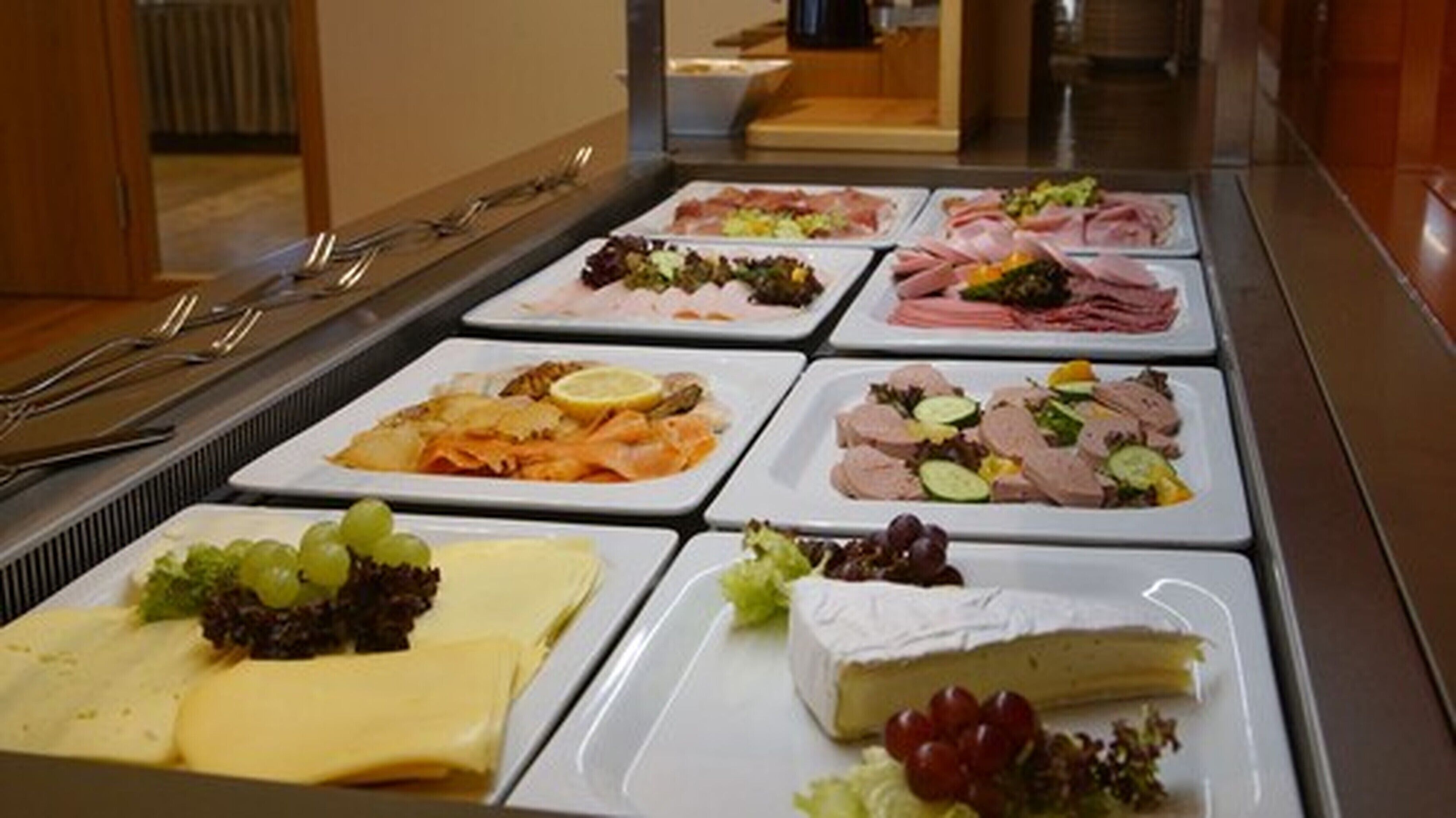 A buffet with various food items including meats, cheeses, and salads.