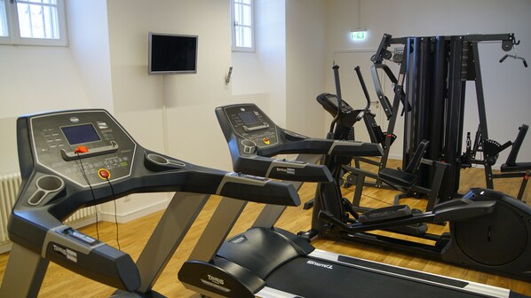 Un gimnasio con equipo de ejercicio, incluyendo cintas de correr y una bicicleta estática.