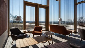 A modern room with large windows, a sofa, two armchairs, and a small table.