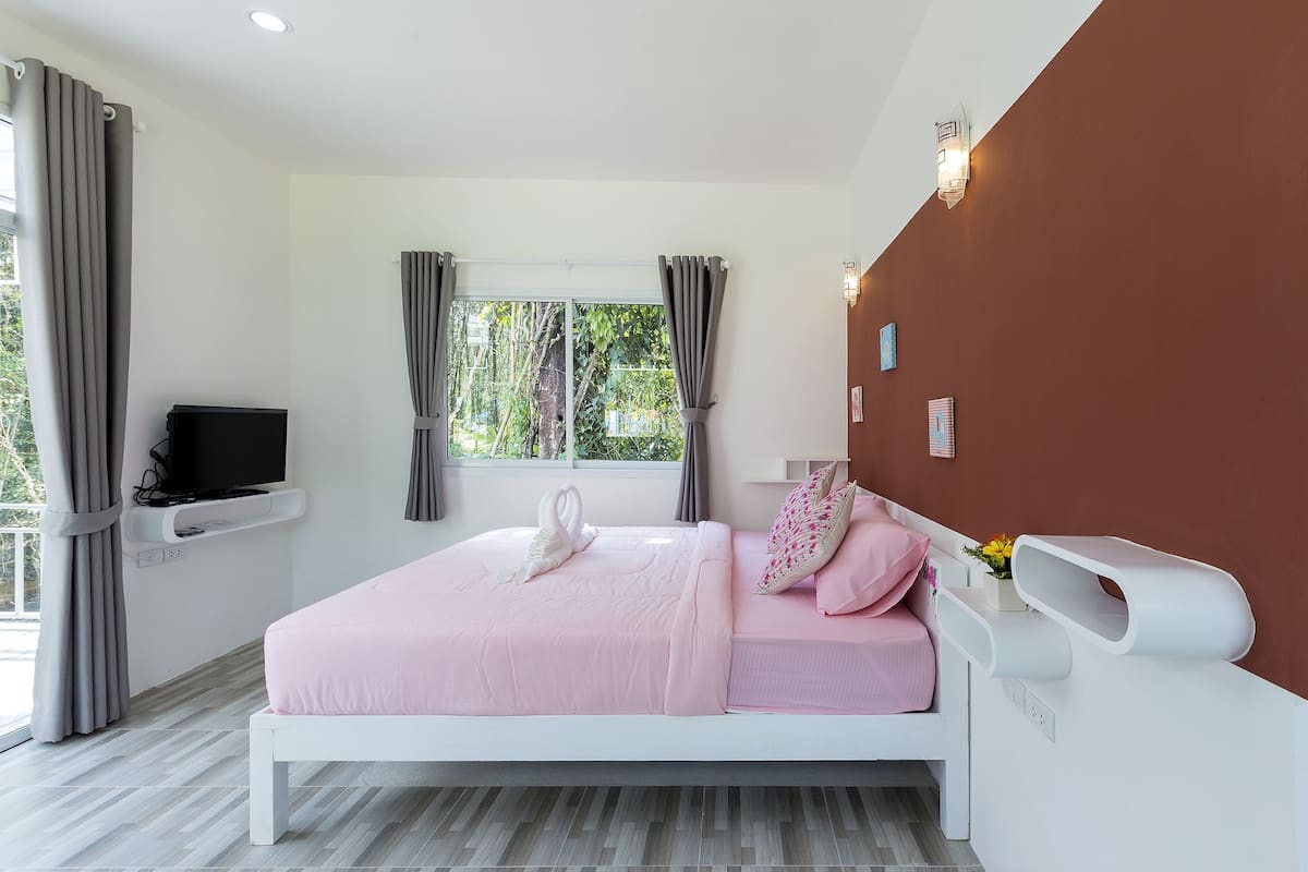 Un dormitorio moderno con una cama, un televisor y una ventana con cortinas.