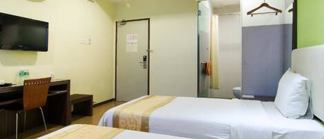 A hotel room with two beds, a desk, a chair, a TV, and a shower area.